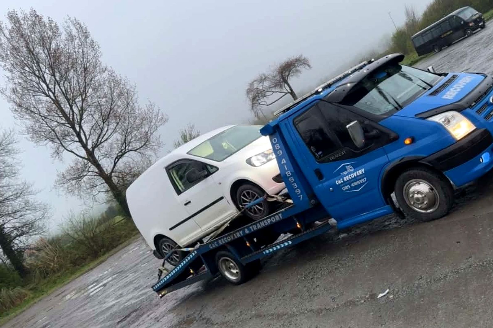 C&C Recovery blue flatbed truck carrying a white van on a wet day near Coolbeg Cross, County Wexford